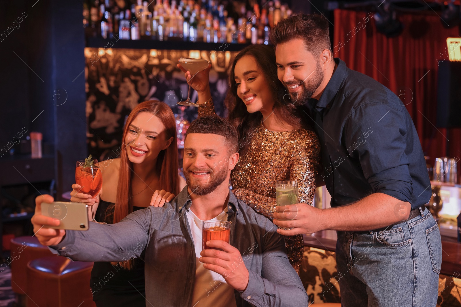 Photo of Happy friends with cocktails taking selfie together in bar