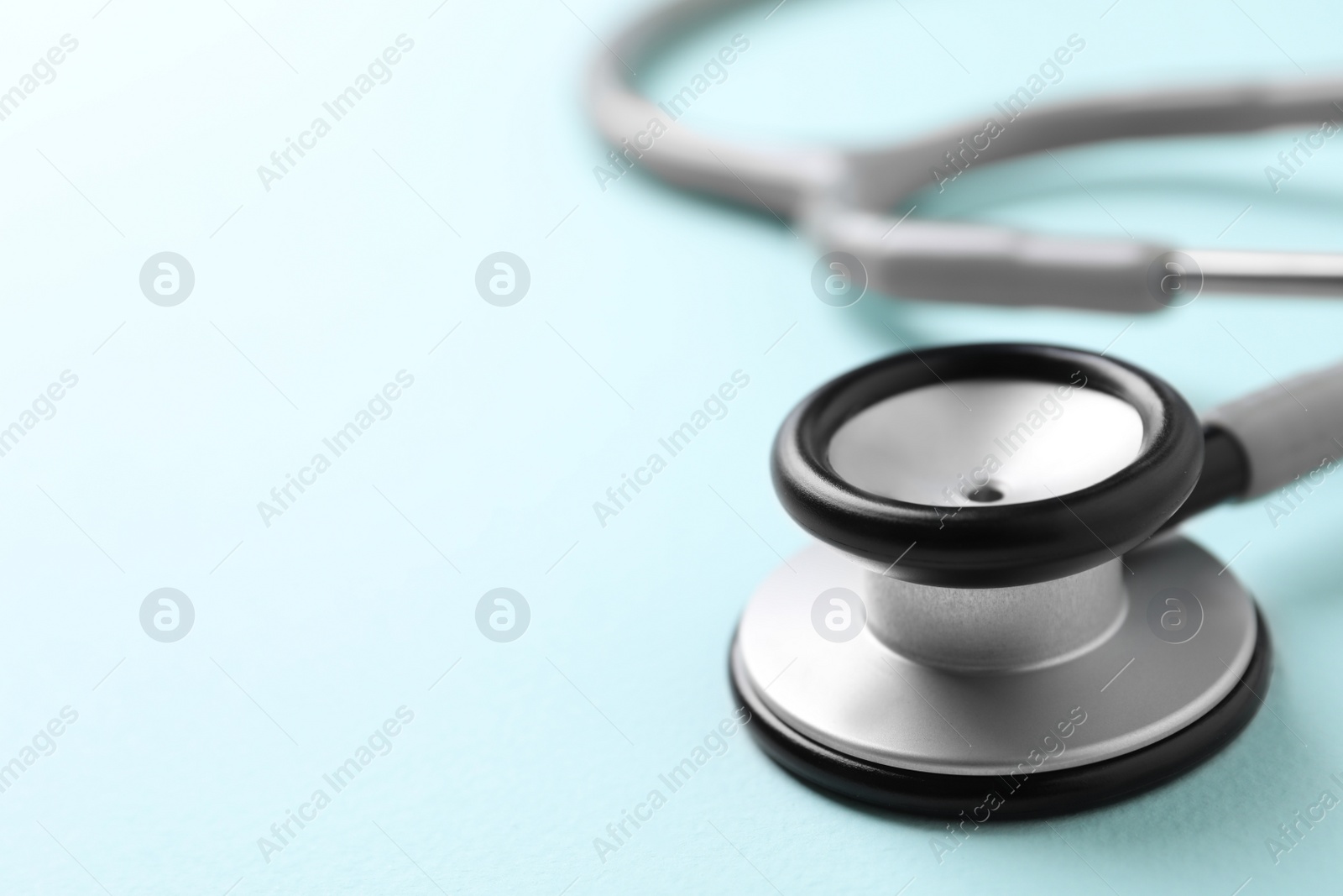 Photo of Stethoscope on light blue background, closeup. Space for text