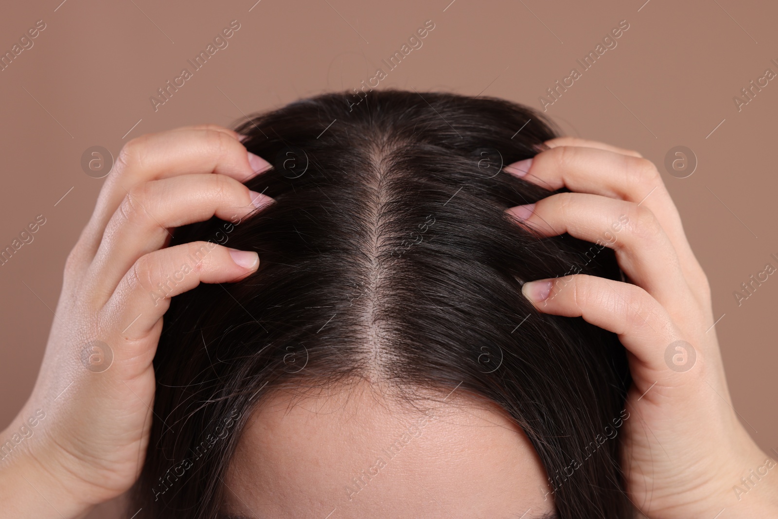 Photo of Woman examining her hair and scalp on beige background, closeup