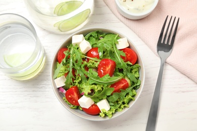 Photo of Delicious salad with arugula and vegetables on white table, flat lay