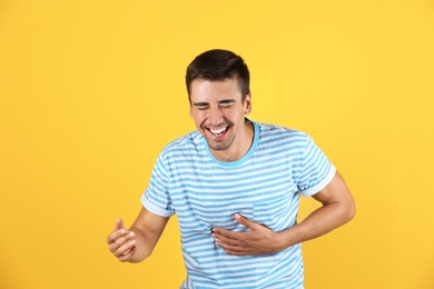 Portrait of handsome young man laughing on color background