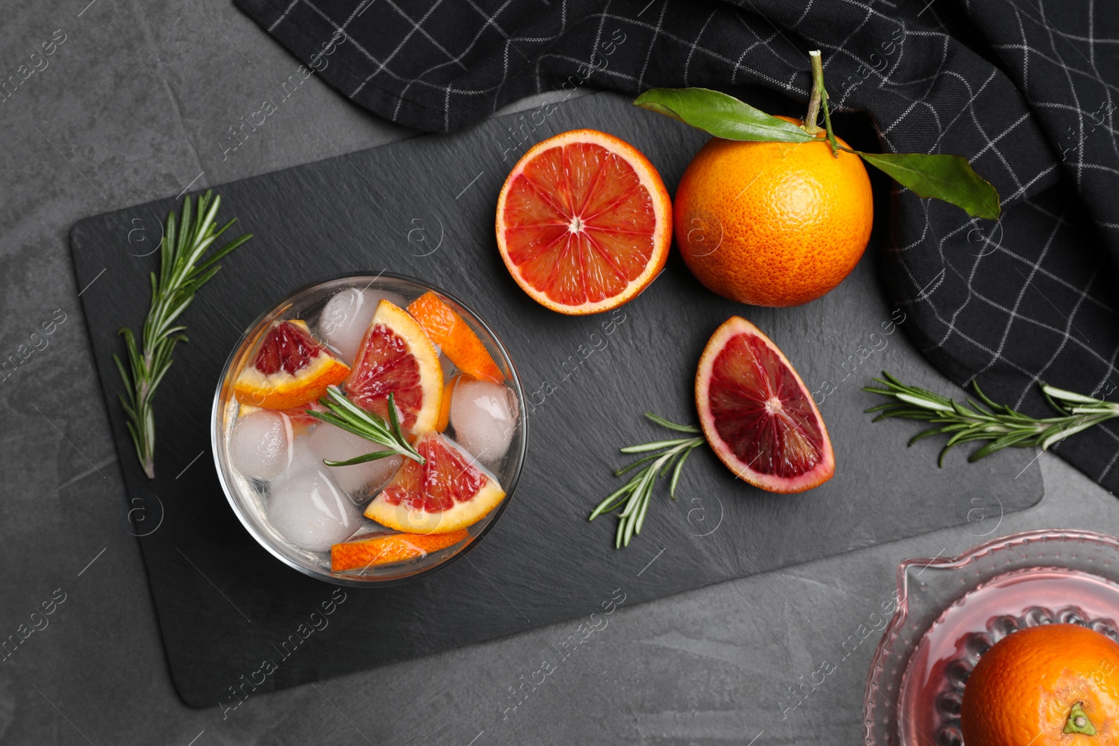 Photo of Delicious refreshing drink with sicilian orange and rosemary near fresh ingredients on grey table, flat lay