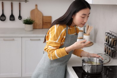 Beautiful woman cooking and smelling soup in kitchen. Space for text
