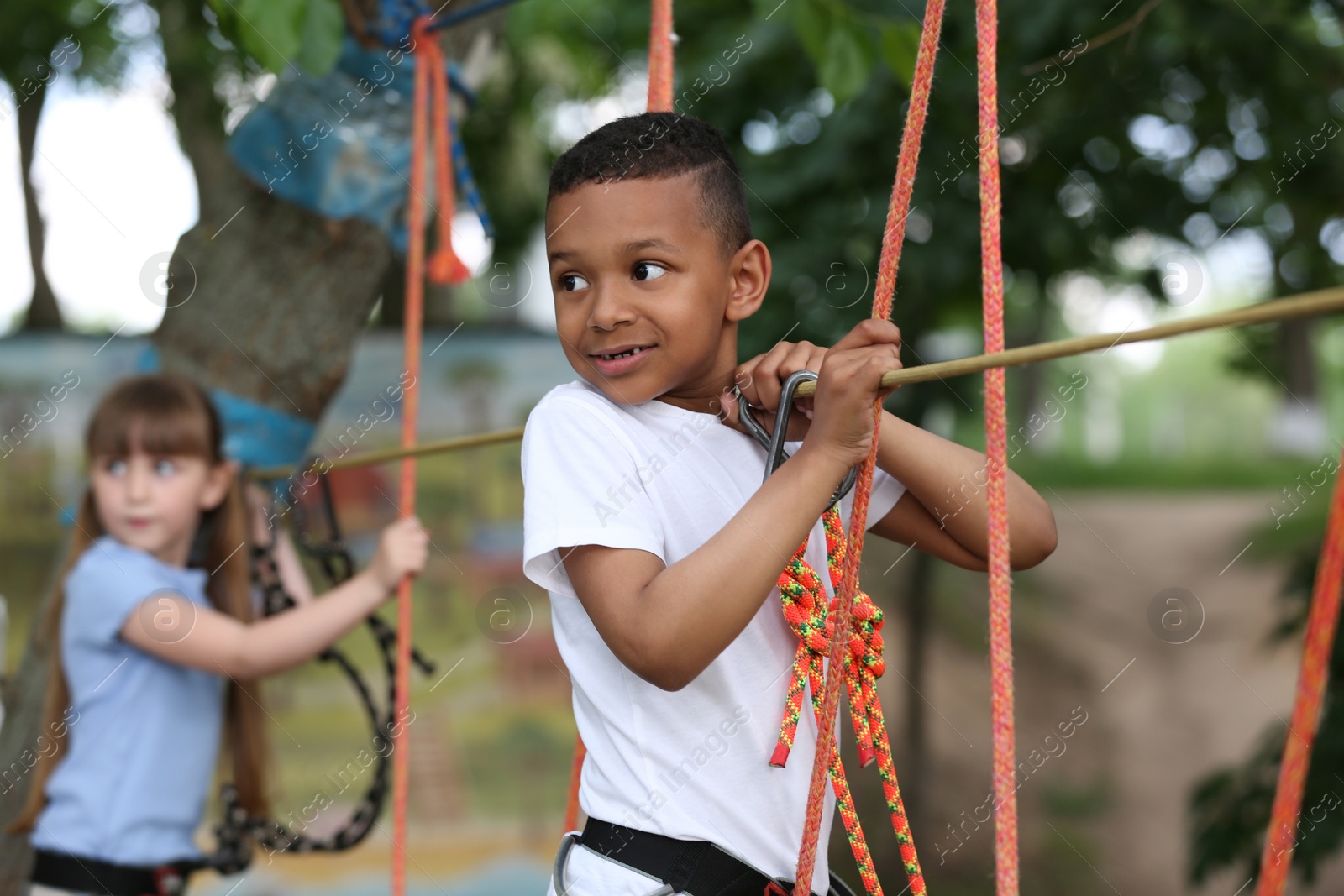 Photo of Little African-American boy climbing in adventure park. Summer camp