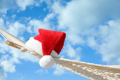 Photo of Rope hammock with Santa's hat outdoors, closeup. Christmas vacation
