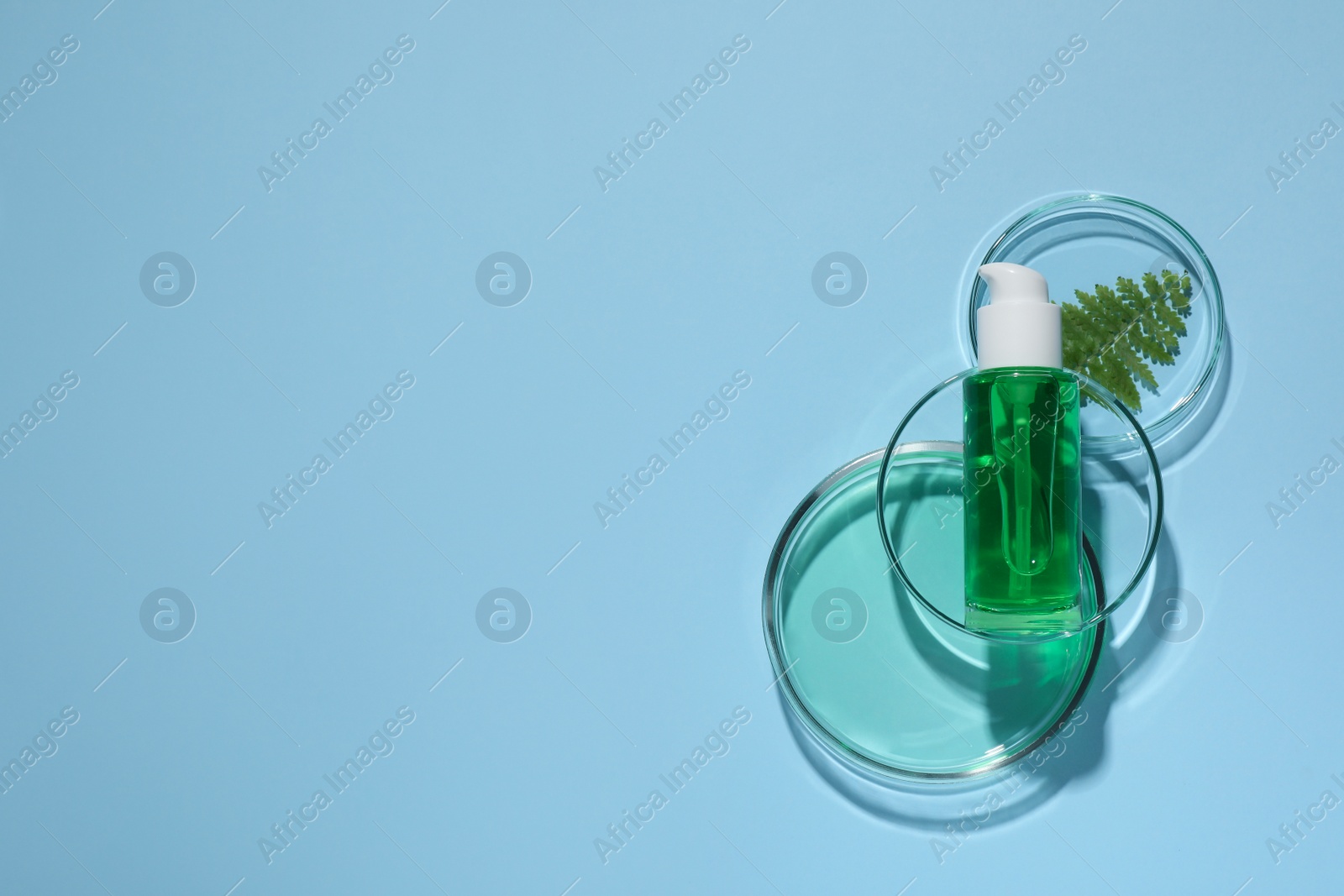 Photo of Organic cosmetic product, natural ingredient and laboratory glassware on light blue background, flat lay. Space for text