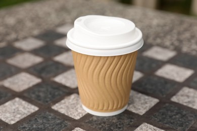 Photo of Paper cup on stone table, closeup. Coffee to go