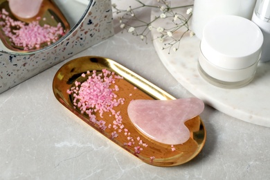 Photo of Rose quartz gua sha tool and sea salt on light table