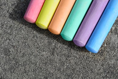 Photo of Colorful chalk sticks on asphalt, flat lay. Space for text