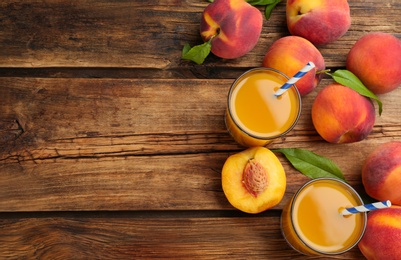 Photo of Natural peach juice and fresh fruits on wooden table, flat lay. Space for text