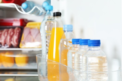Photo of Bottles of beverages on refrigerator door shelf, closeup