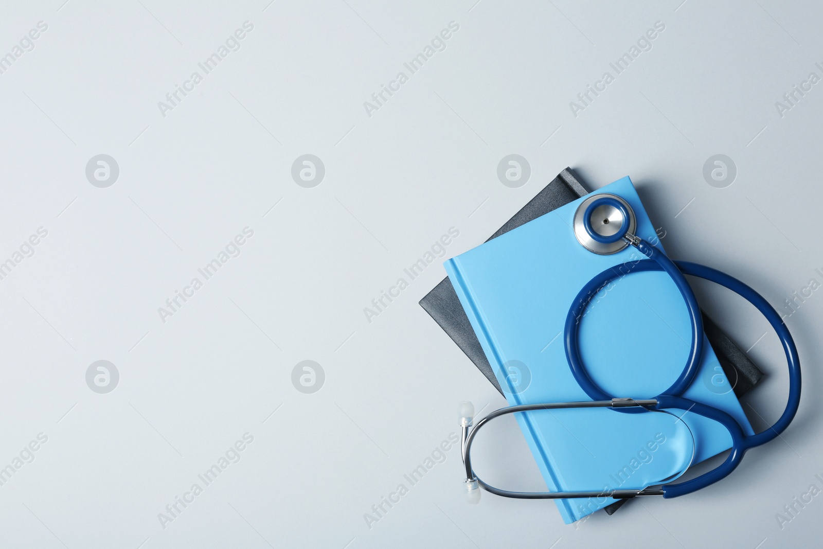 Photo of Student textbooks, stethoscope and space for text on grey background. Medical education