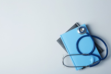 Student textbooks, stethoscope and space for text on grey background. Medical education