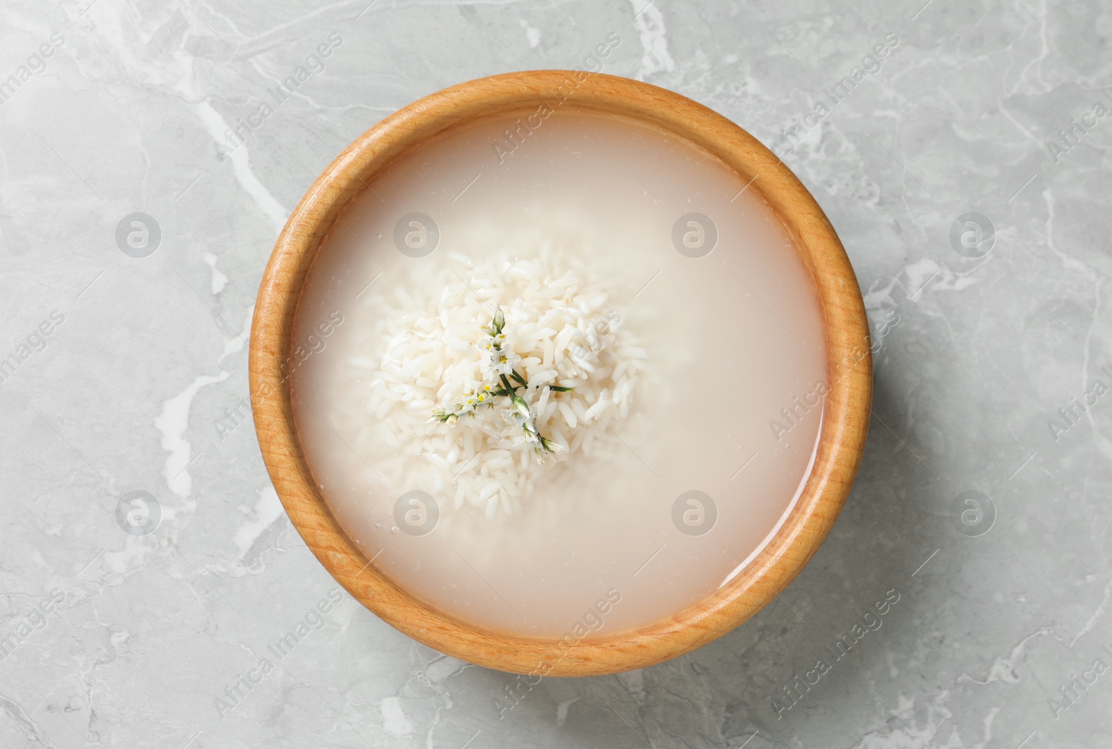 Photo of Bowl with rice soaked in water on light grey marble table, top view