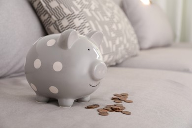 Photo of Grey piggy bank and coins on sofa