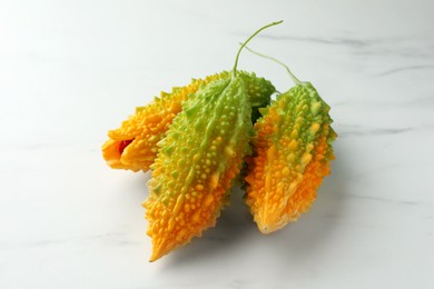 Photo of Beautiful bitter melons on white marble table, closeup