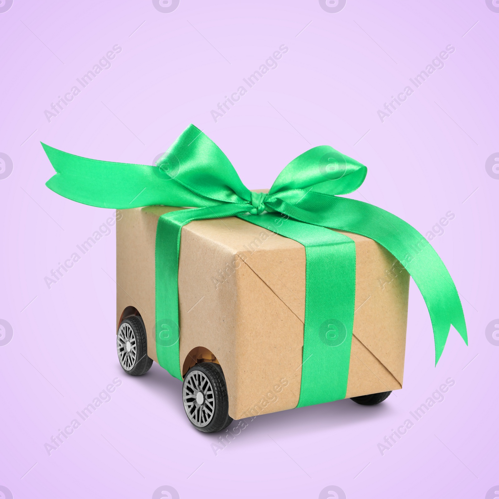 Image of Gift box on wheels against pale violet background. Delivery service