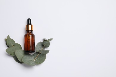 Photo of Aromatherapy product. Bottle of essential oil and eucalyptus leaves on white background, flat lay. Space for text