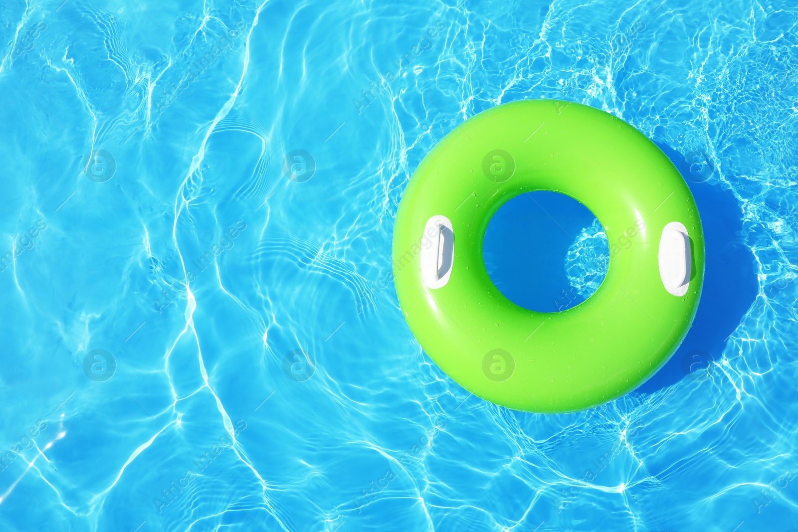 Photo of Inflatable ring floating in swimming pool on sunny day, top view with space for text