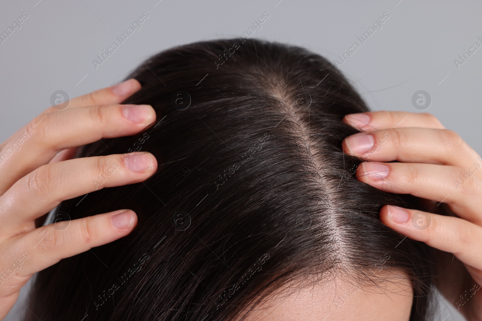 Photo of Woman examining her hair and scalp on grey background, closeup