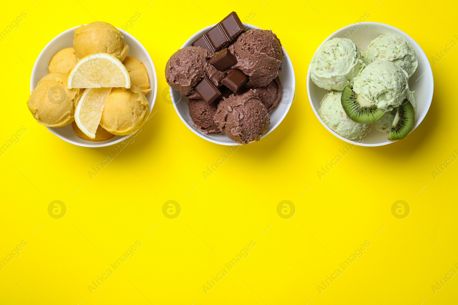 Photo of Different delicious ice creams on yellow background, flat lay. Space for text