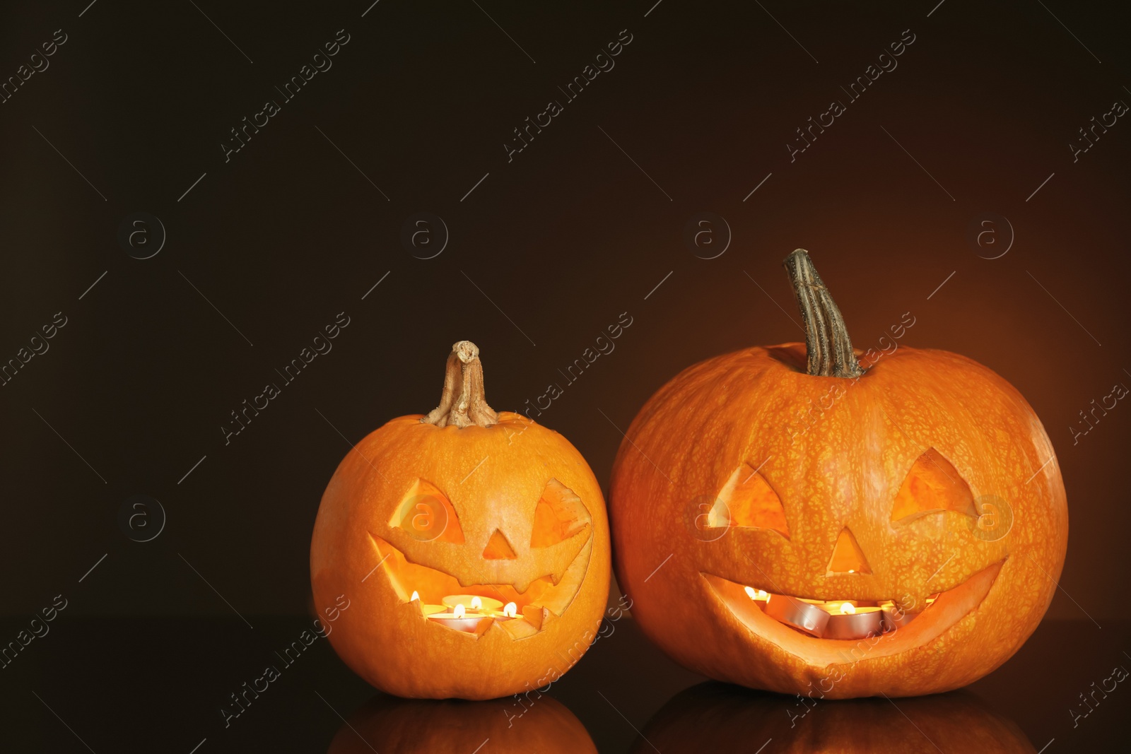 Photo of Halloween pumpkin heads. Glowing jack lanterns on dark background