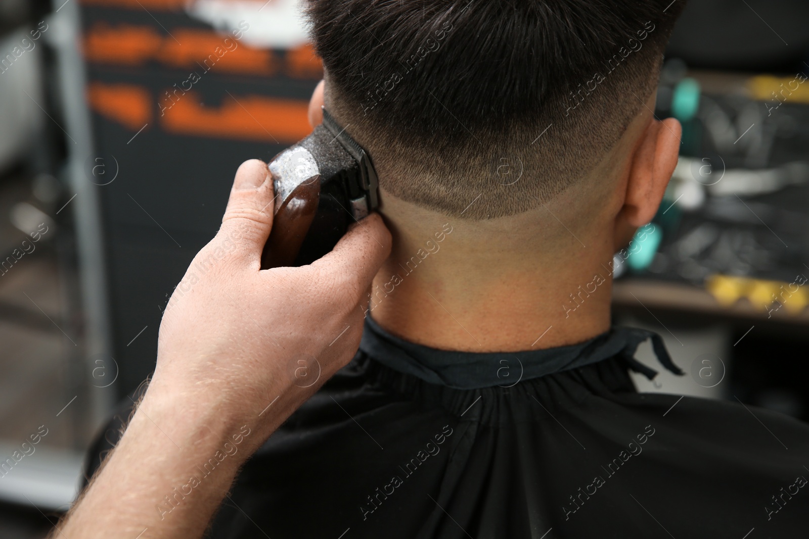 Photo of Professional barber making stylish haircut in salon, closeup