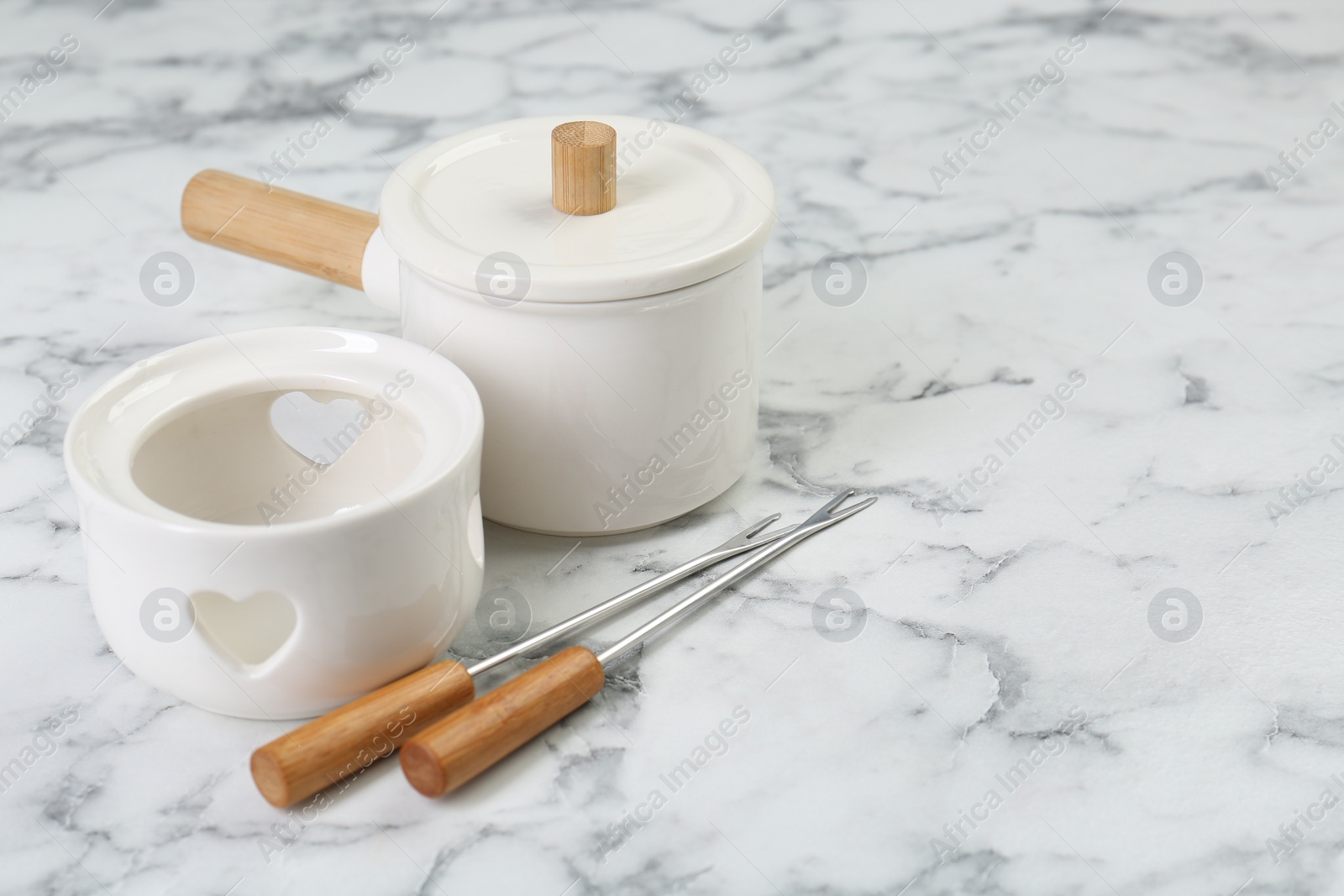 Photo of Fondue set on white marble table, space for text