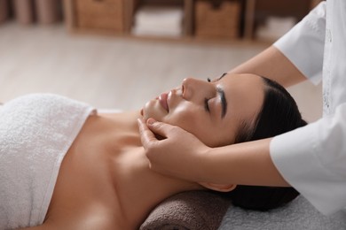 Photo of Young woman enjoying professional massage in spa salon