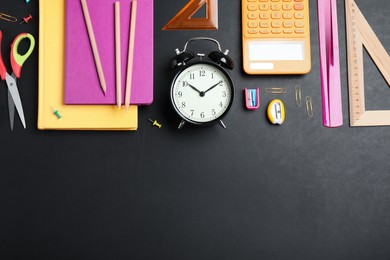 Photo of Flat lay composition with alarm clock and different stationery on blackboard, space for text. School time
