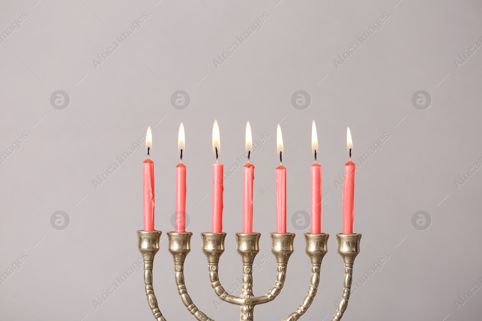 Photo of Golden menorah with burning candles on light grey background, space for text