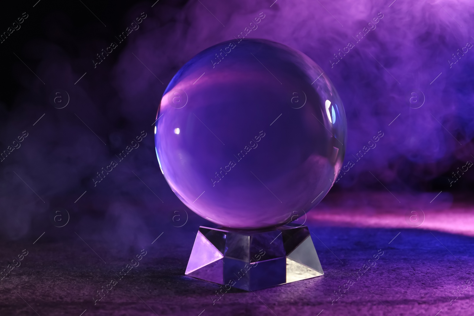 Photo of Crystal ball on table and smoke against dark background. Predictions of future