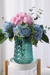 Beautiful hortensia flowers in vase on stand indoors