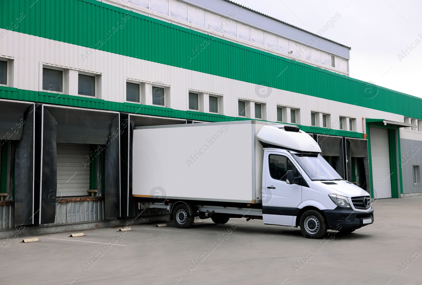 Image of Truck near loading dock of warehouse outdoors. Logistics center