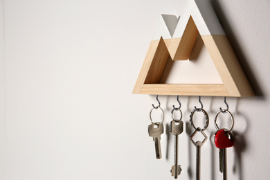 Photo of Wooden key holder on light grey wall. Space for text