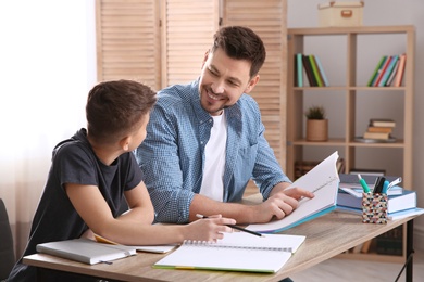 Dad helping his son with homework in room