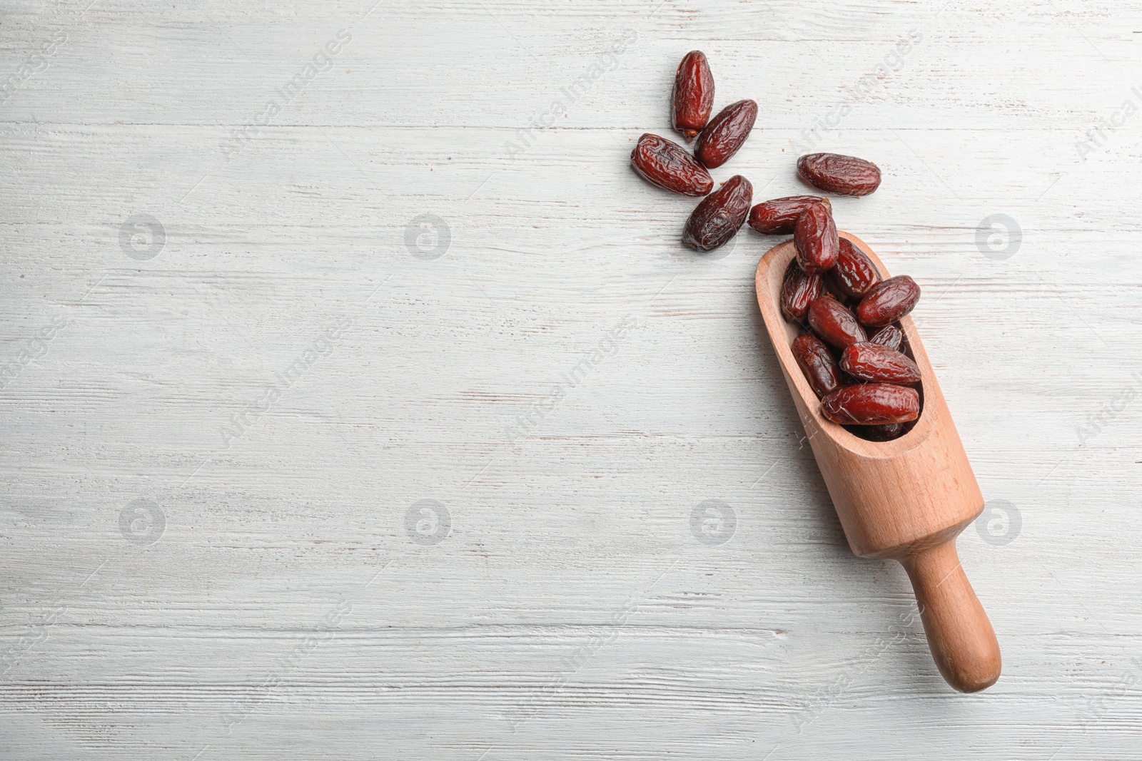 Photo of Scoop with sweet dried date fruits on wooden background, top view. Space for text