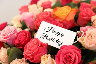 Bouquet of beautiful roses with Happy Birthday card, closeup