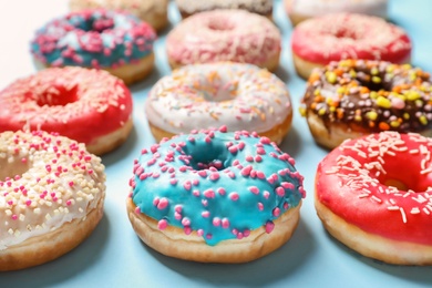 Delicious glazed doughnuts with sprinkles on color background