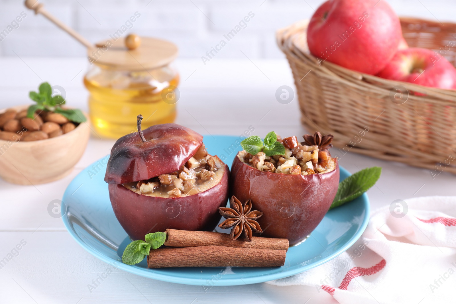 Photo of Tasty baked apples with nuts, honey, spices and mint on white wooden table