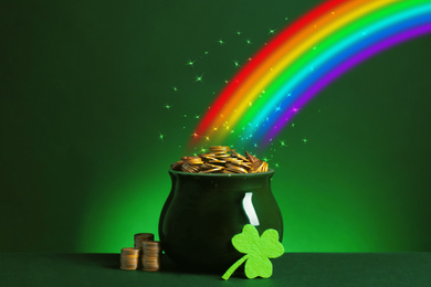 Pot with gold coins and clover on table against dark background. St. Patrick's Day