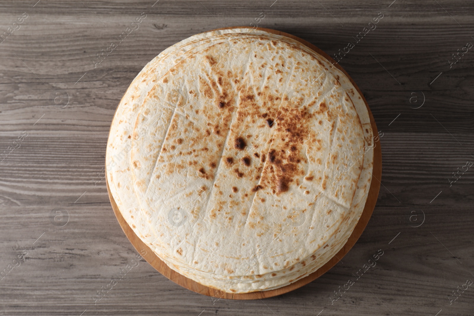 Photo of Many tasty homemade tortillas on wooden table, top view