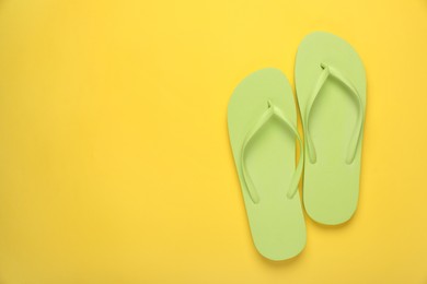 Stylish light green flip flops on yellow background, top view. Space for text