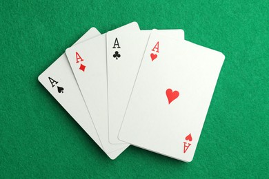 Photo of Four aces playing cards on green table, top view. Poker game