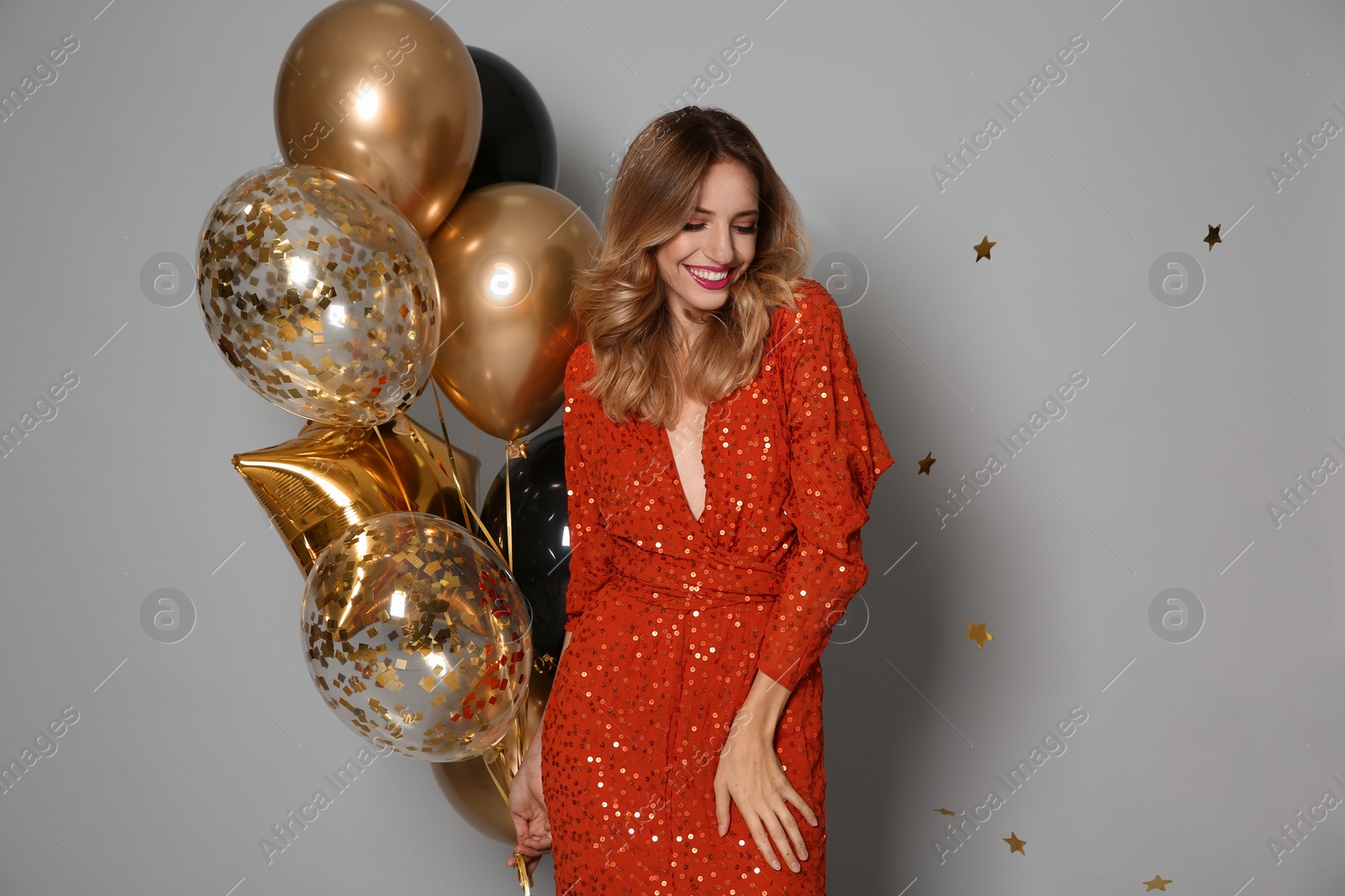 Photo of Happy woman with air balloons on grey background. Christmas party