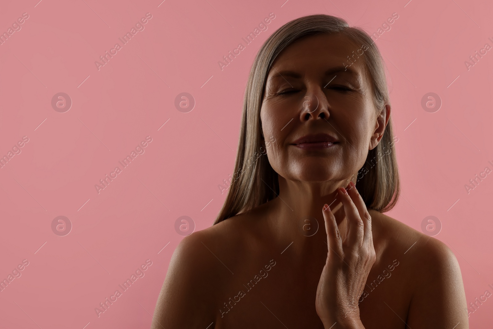 Photo of Beautiful woman touching her neck on pink background, space for text