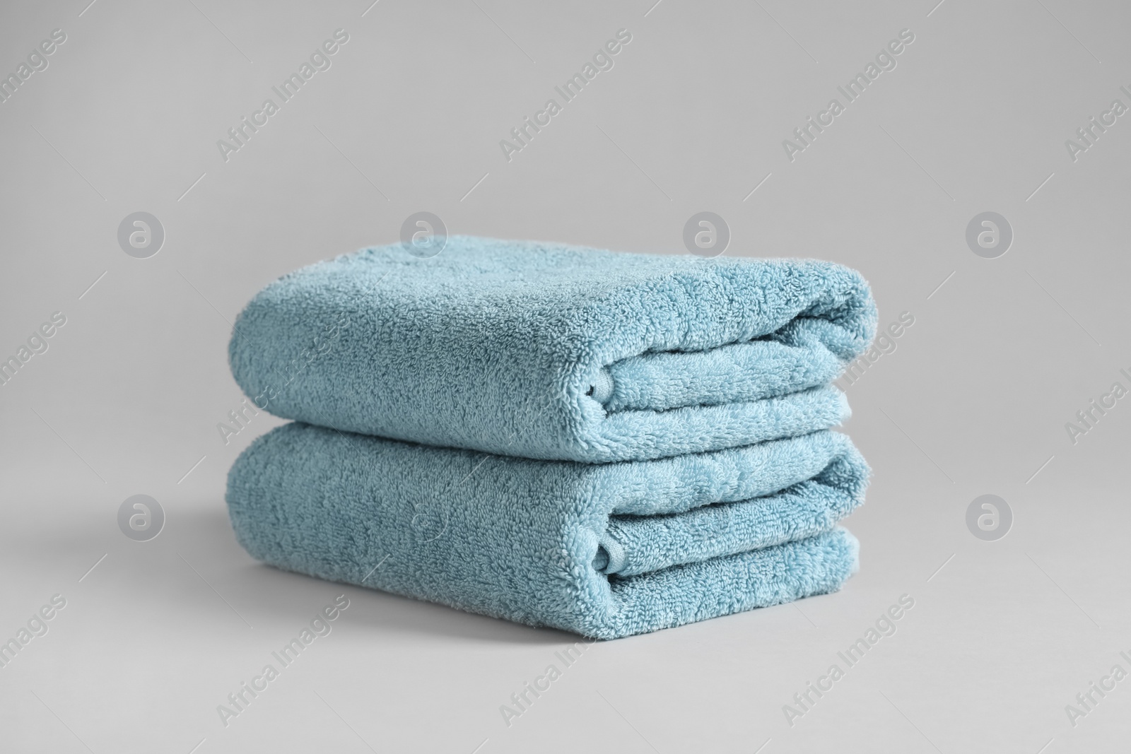 Photo of Stack of fresh fluffy towels on grey background