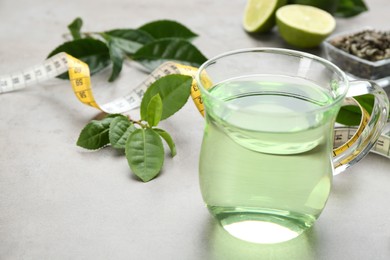 Photo of Herbal diet tea, lime and measuring tape on light table