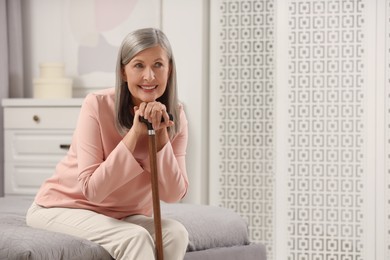 Photo of Mature woman with walking cane on bed at home