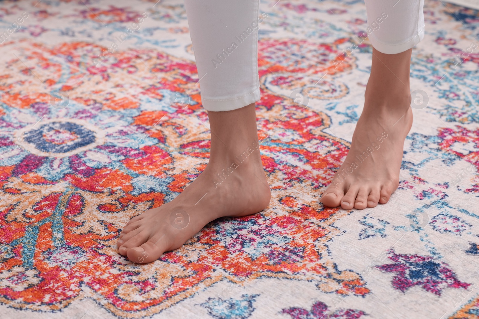 Photo of Woman standing on carpet with pattern at home, closeup